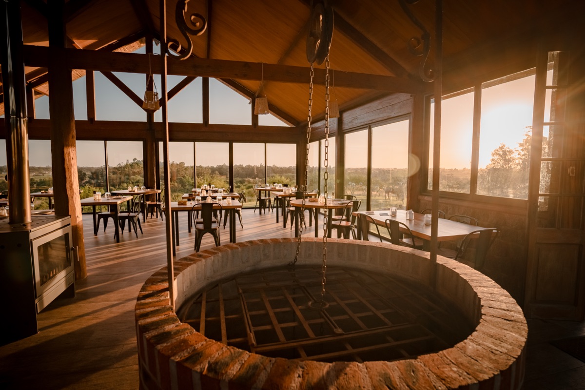 Interior de Chocha y Nena - salon con pozo de fuego y mesas con vista al campo